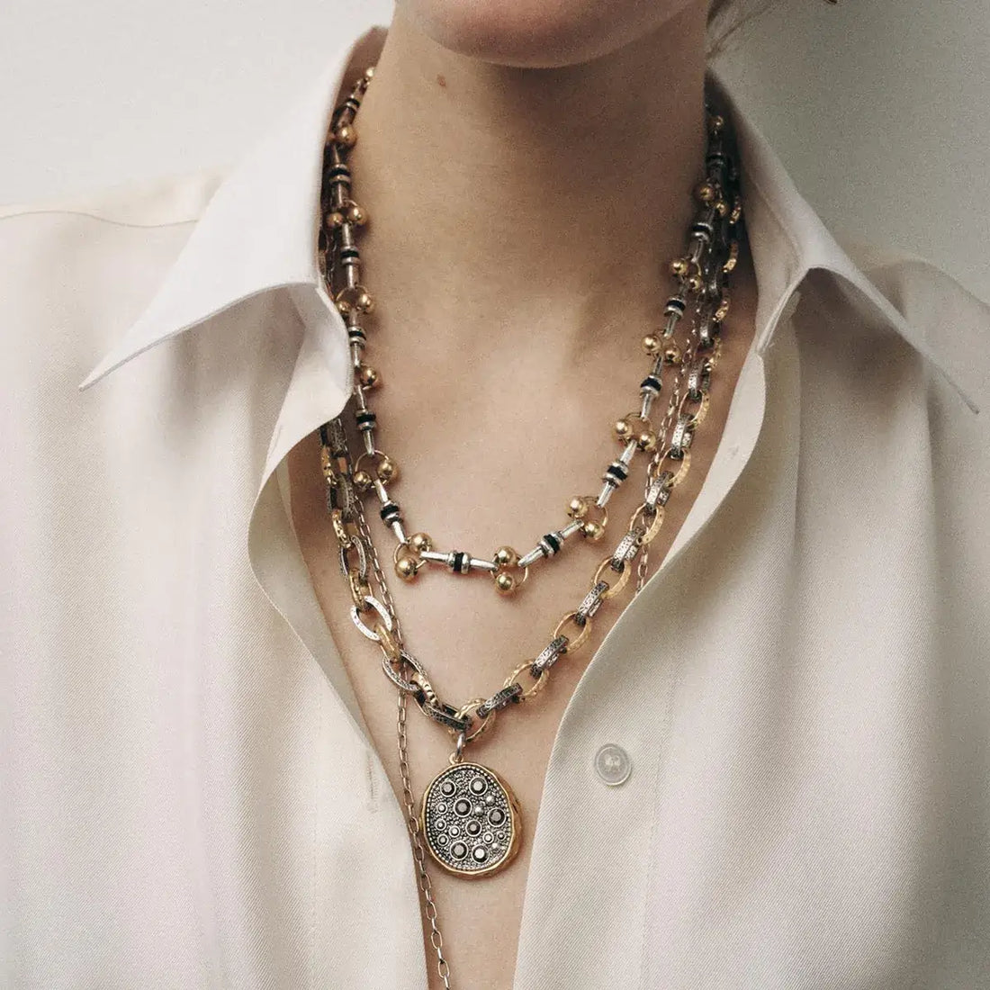 3-piece layered stainless steel necklace set with sculptural pendants on a model.