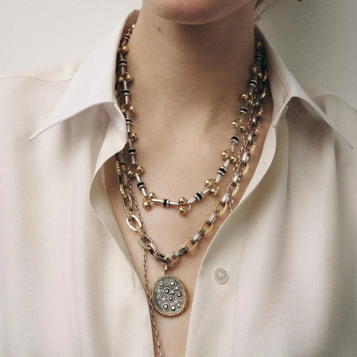 3-piece layered stainless steel necklace set with sculptural pendants on a model.